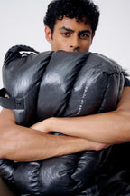 Person holding a large black bag with 'Tote' branding on a white background