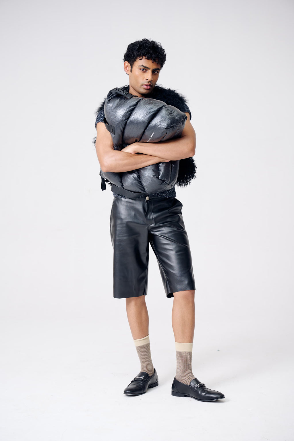 Person wearing a futuristic outfit with a metallic vest and shorts on a white background