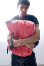 Person holding a pink puffer bag against a white background