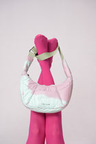 Pink quilted handbag with a pink sock on a light pink background