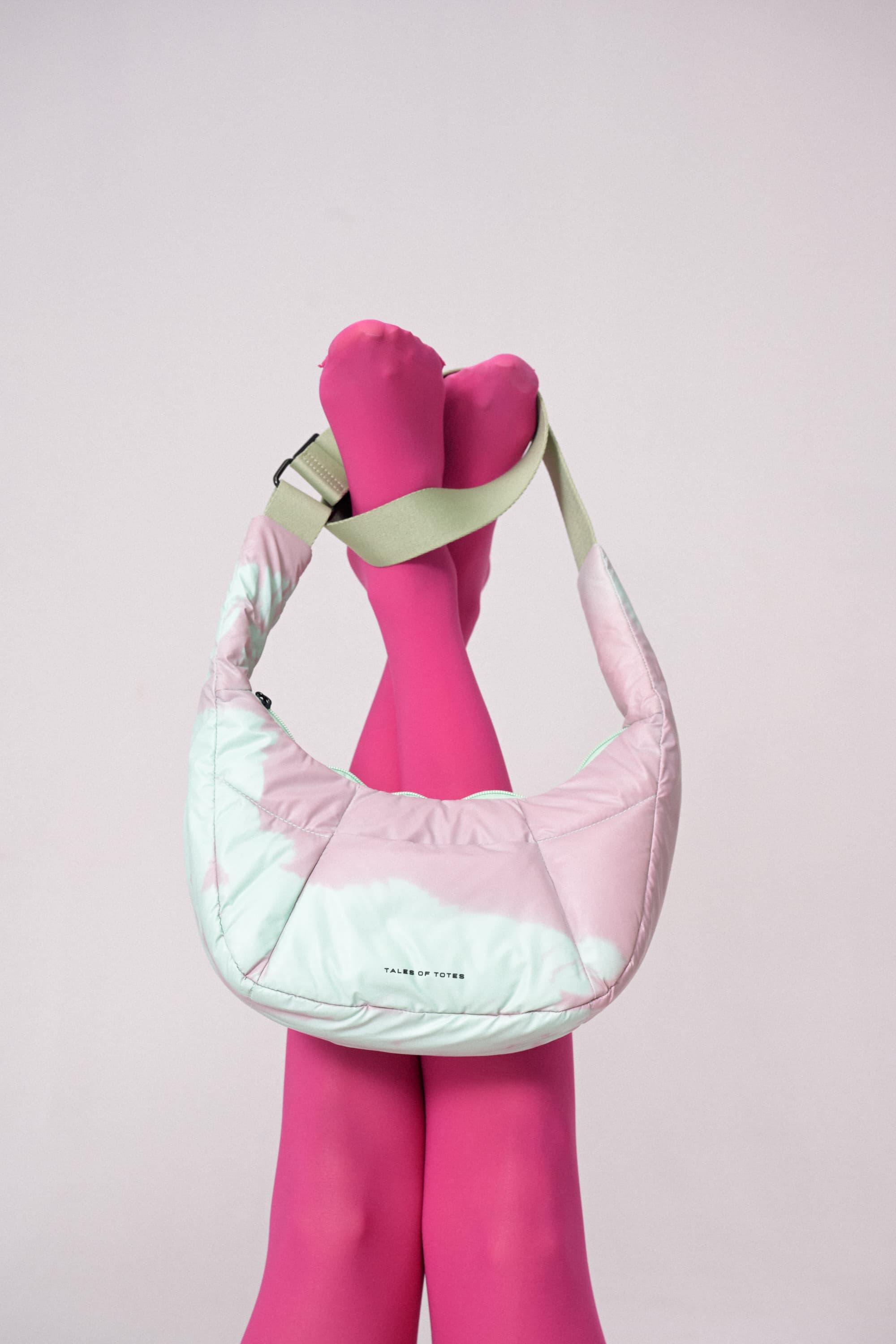 Pink quilted handbag with a pink sock on a light pink background