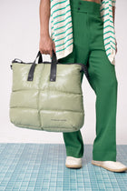 Person holding a green puffer bag with a white background