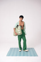 Man holding a green bag on a checkered platform with a white background