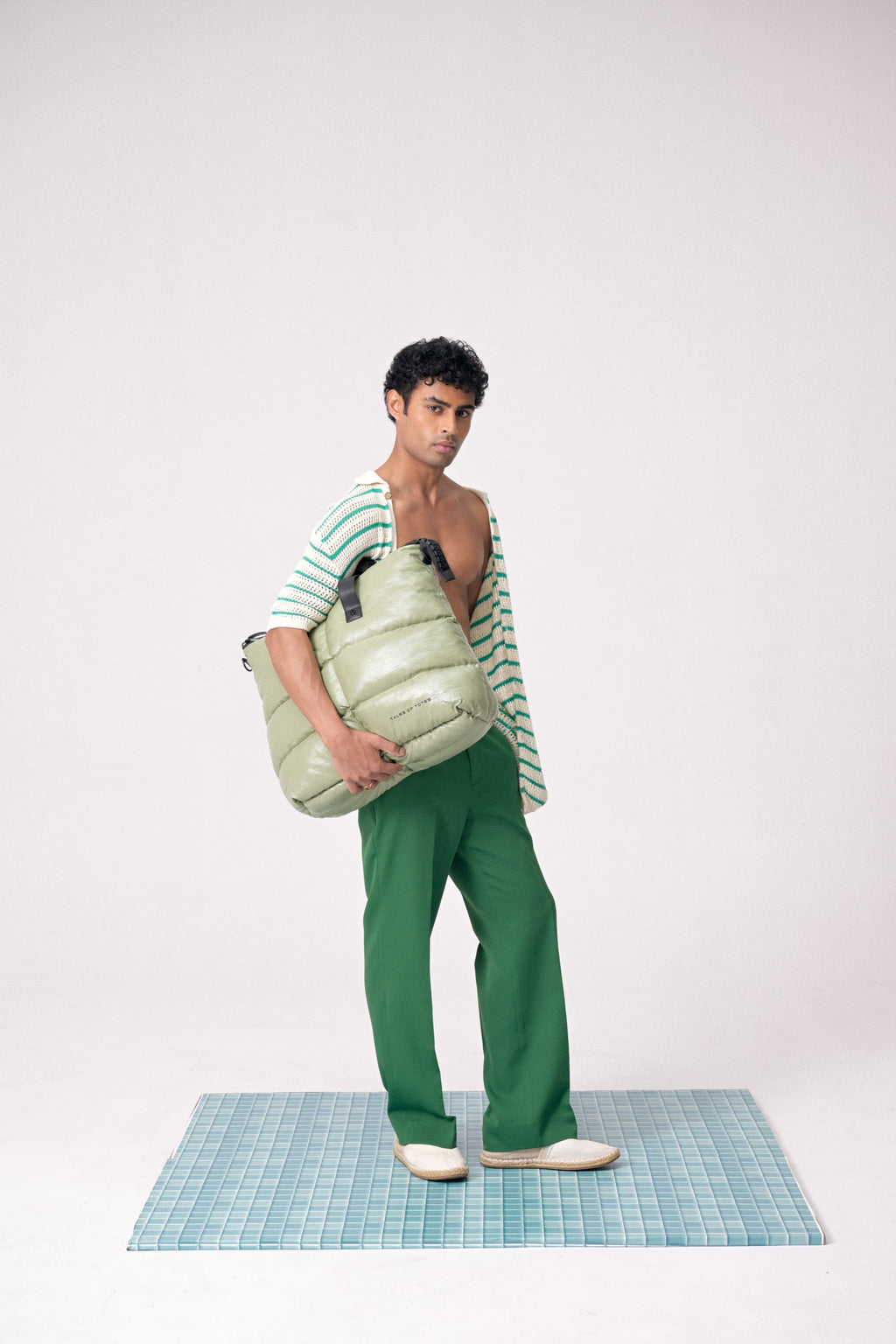 Man holding a large green bag on a white background
