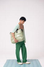 Person holding a large green bag against a white background