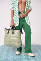 Person wearing a green outfit with a puffer bag on a checkered floor.