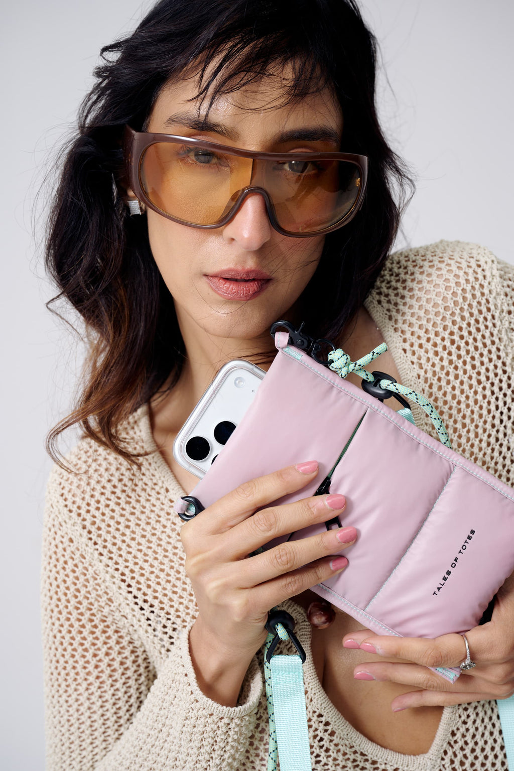 Woman holding a pink wallet and phone with a plain background