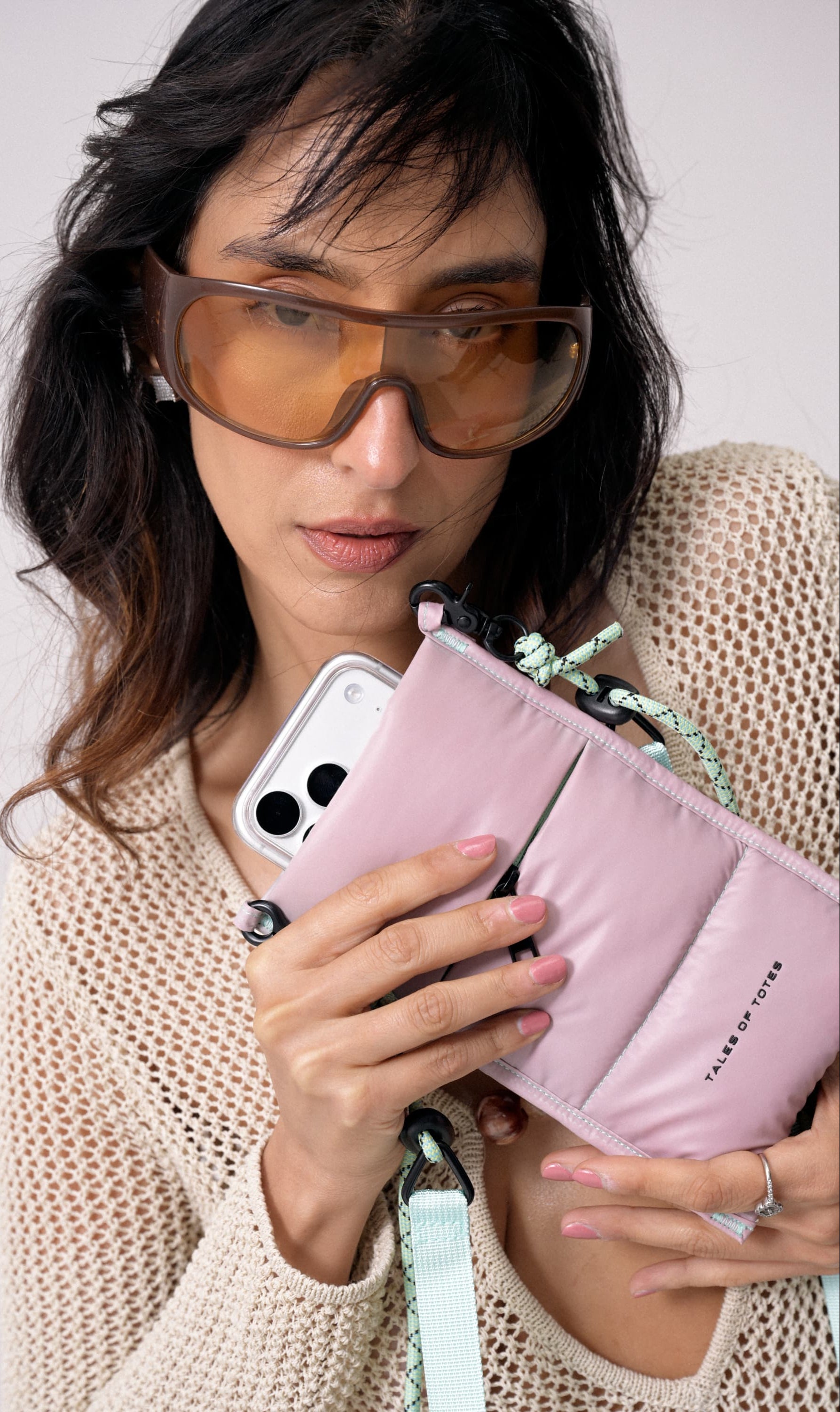 Woman holding a pink phone case and wallet with a white background