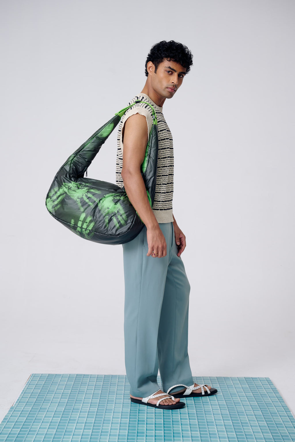 Man holding a green and black patterned bag on a white background