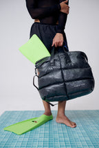 Person holding a black puffer bag with a white background