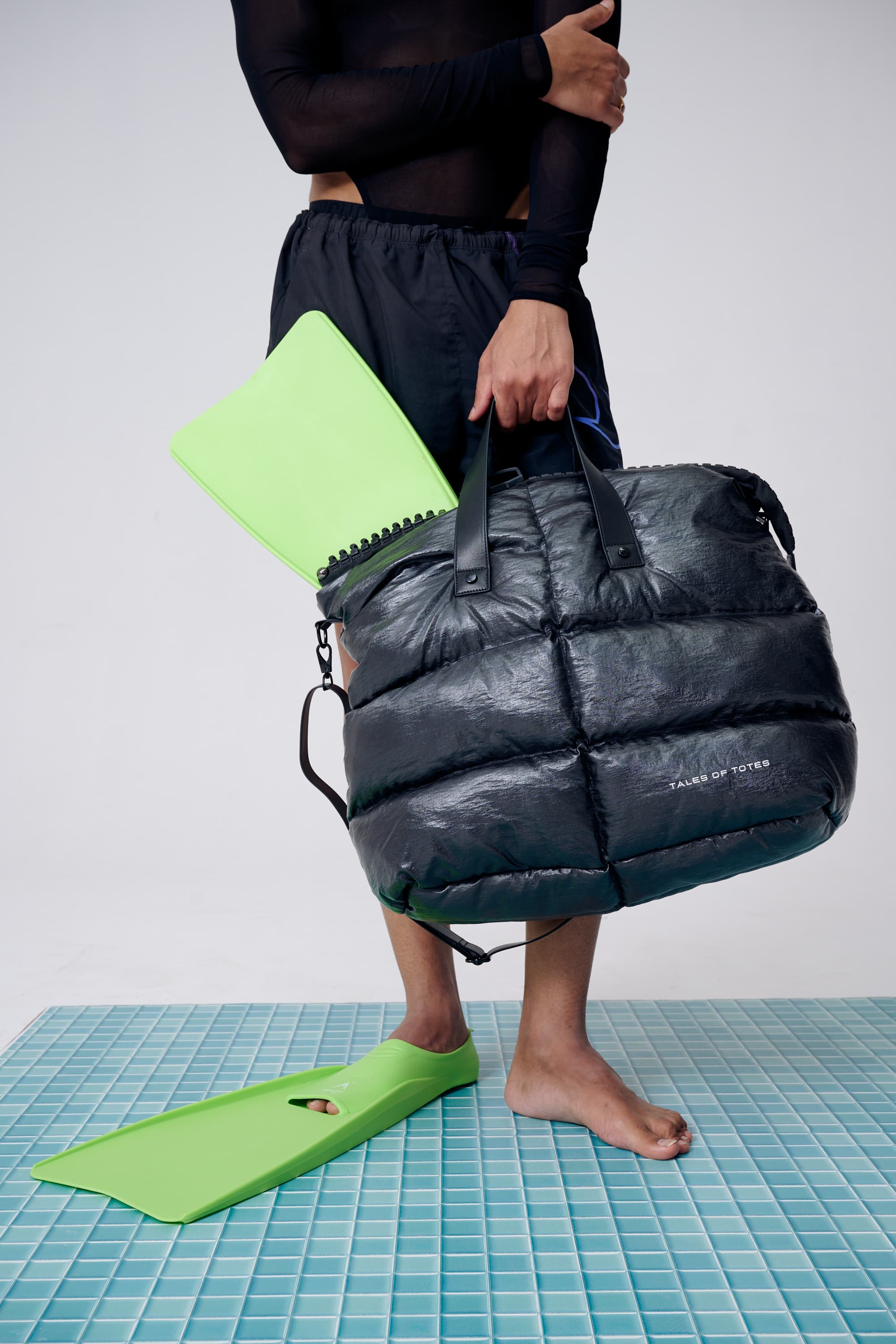 Person holding a black puffer bag with a white background