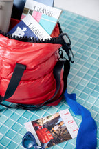 Red bag with 'LifeWear' books and a photo album on a blue tiled surface