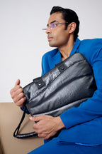 Man in a blue suit holding a black leather briefcase against a white background