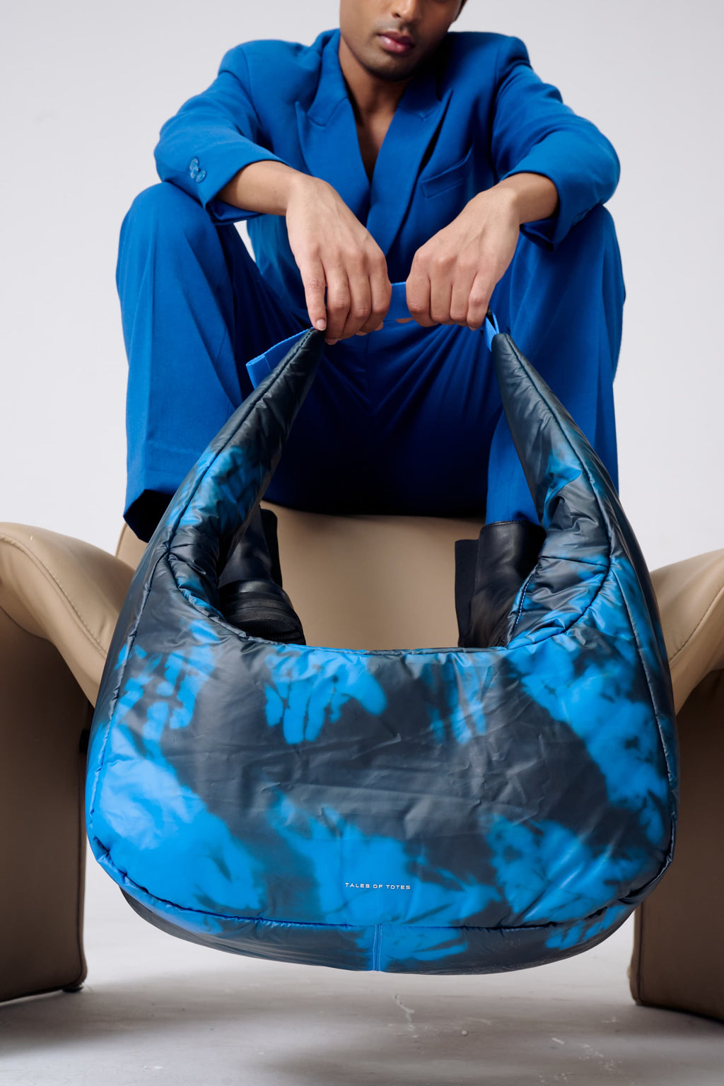 Person holding a blue and black patterned bag against a neutral background