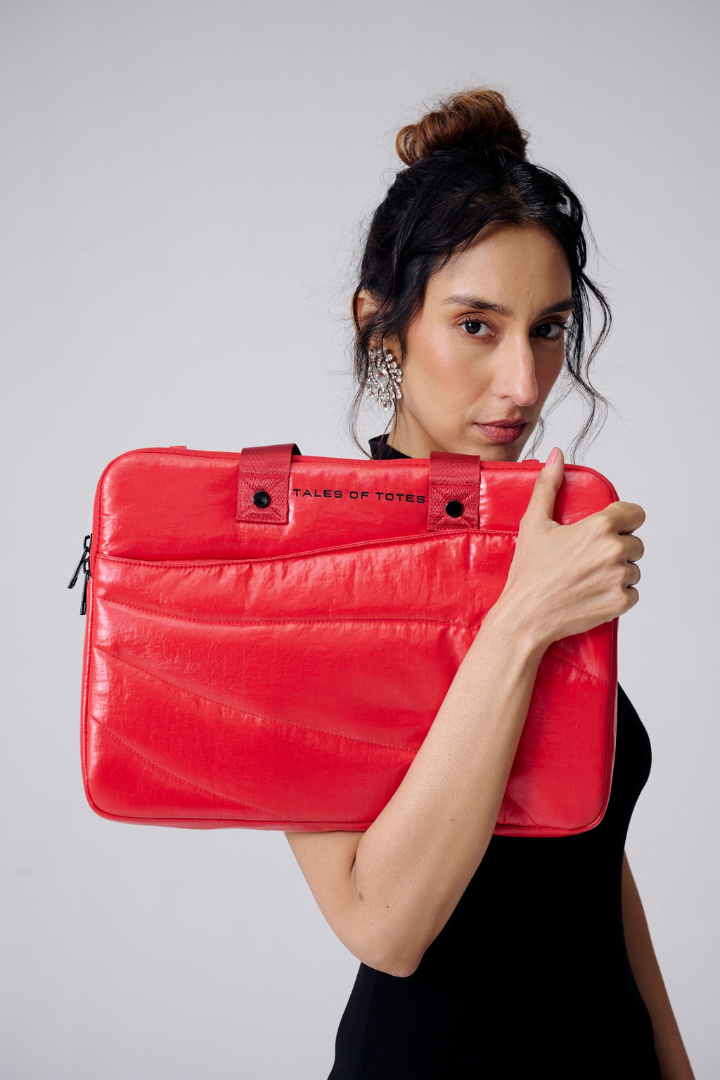 Woman holding a red laptop case with a visible brand logo against a plain background