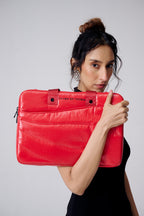 Woman holding a red laptop case with a visible brand logo against a plain background