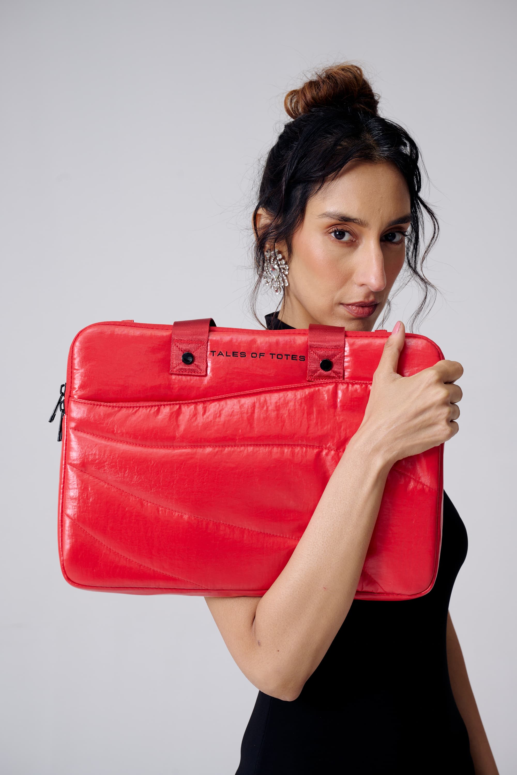 Woman holding a red laptop case with a visible brand logo against a plain background