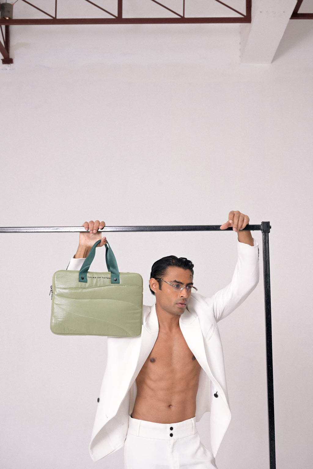 Man holding a green bag above his head against a white background