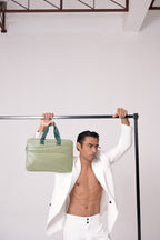 Man holding a green bag above his head against a white background