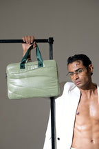 Man holding a green bag against a gray background