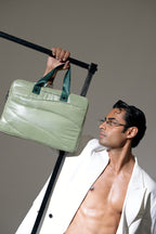 Man holding a green leather bag against a gray background
