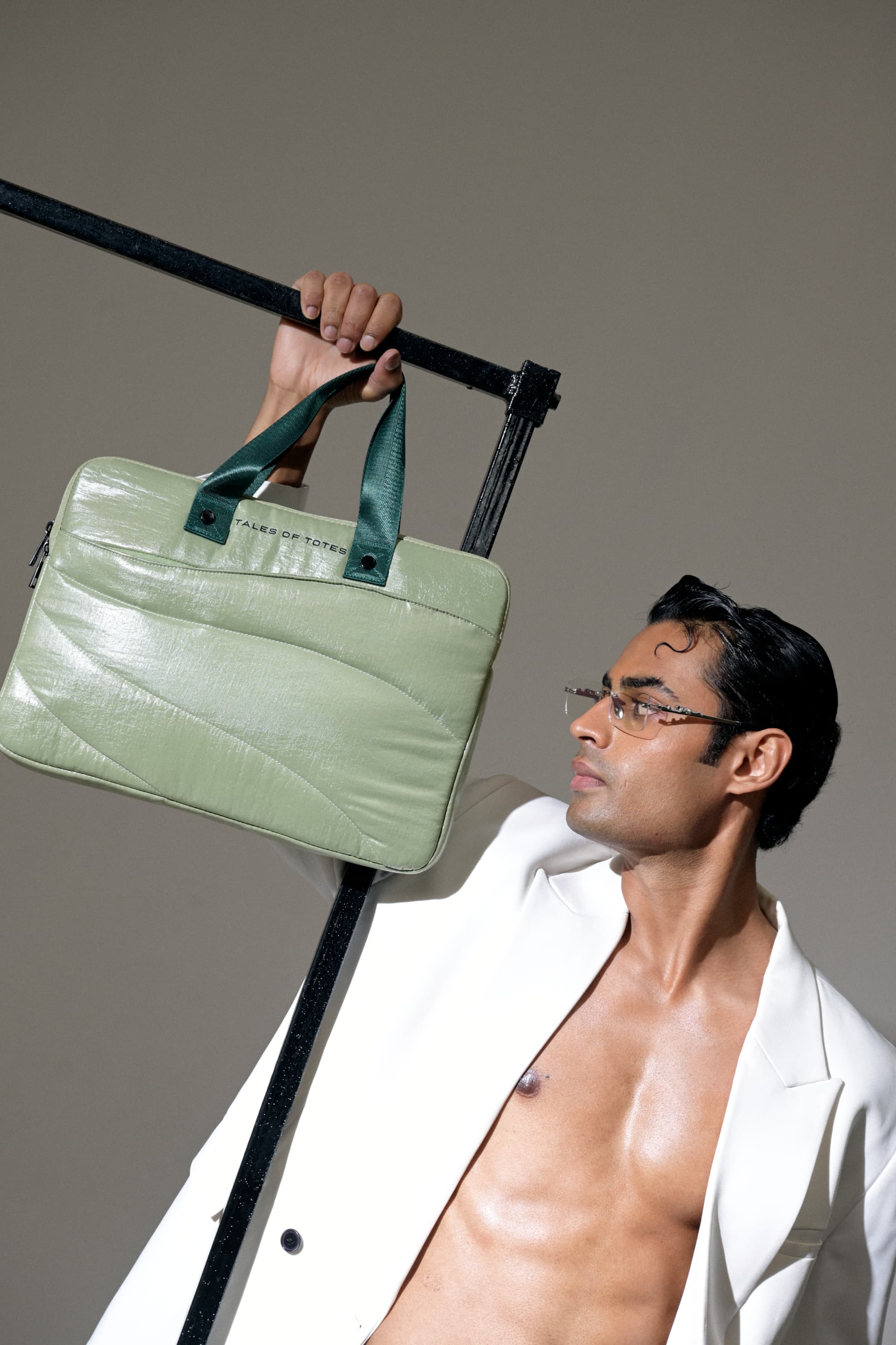 Man holding a green leather bag against a gray background