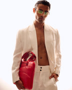 Man wearing a white suit holding a red bag against a white background