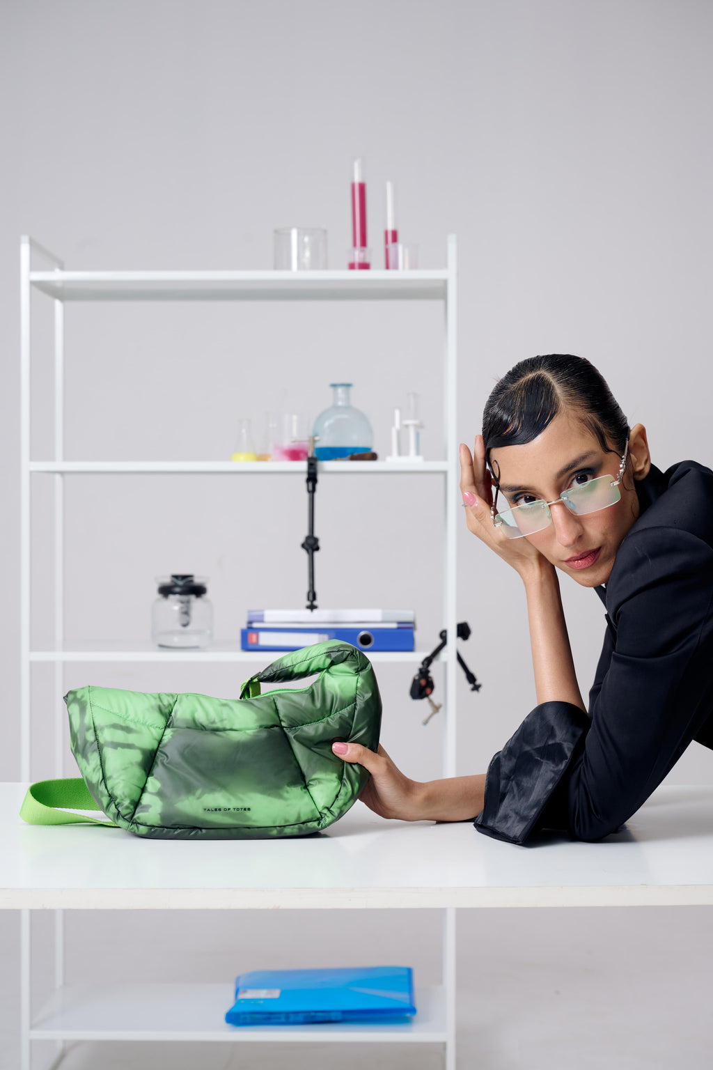 Person holding a green bag in a laboratory setting with shelves and lab equipment.