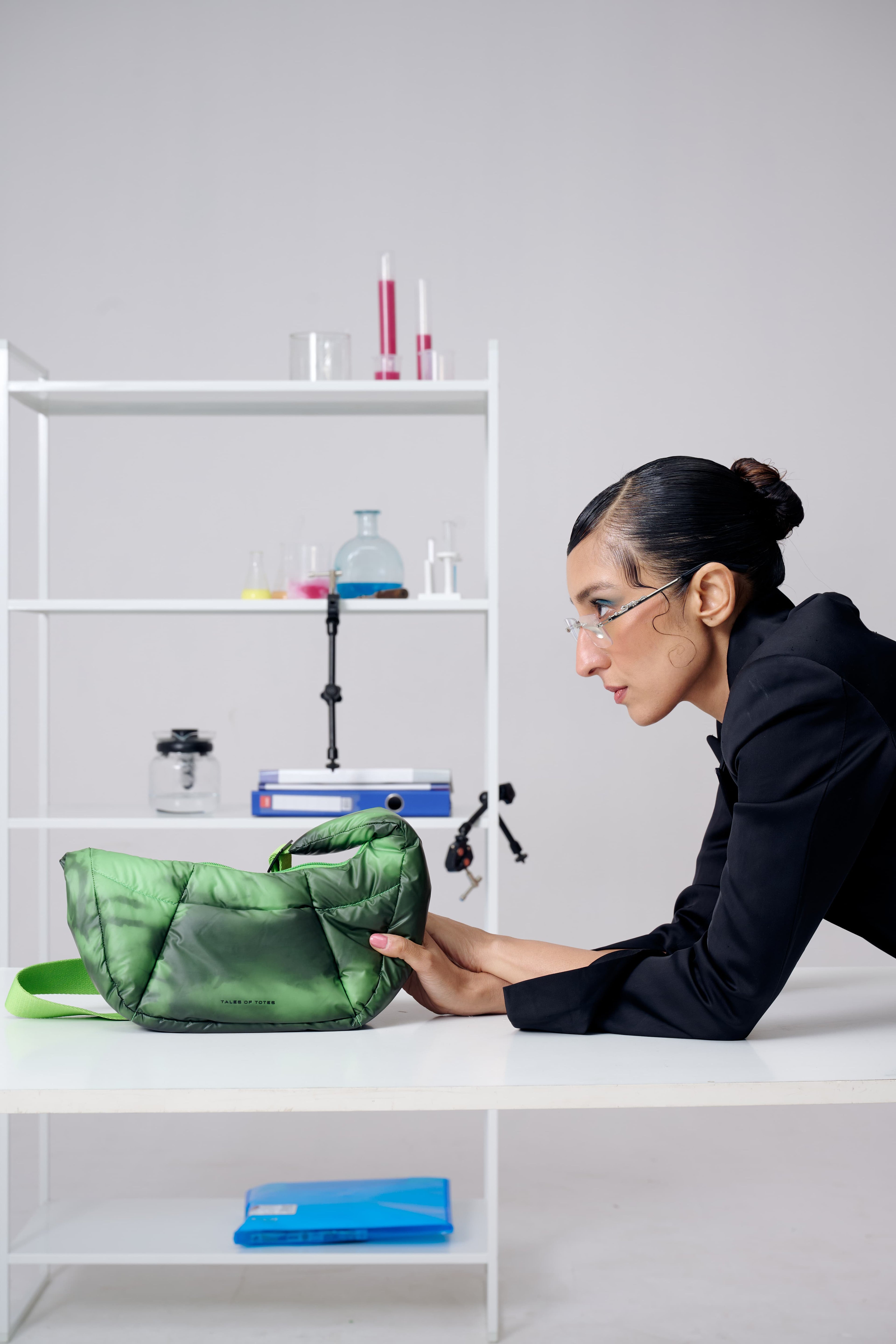 Person interacting with a green bag on a white shelf against a light gray background
