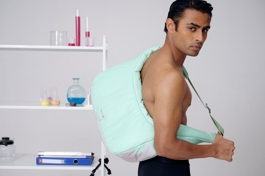 Man wearing a green and white back massager in a room with shelves in the background.