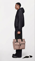 Person holding a beige tote bag against a white background