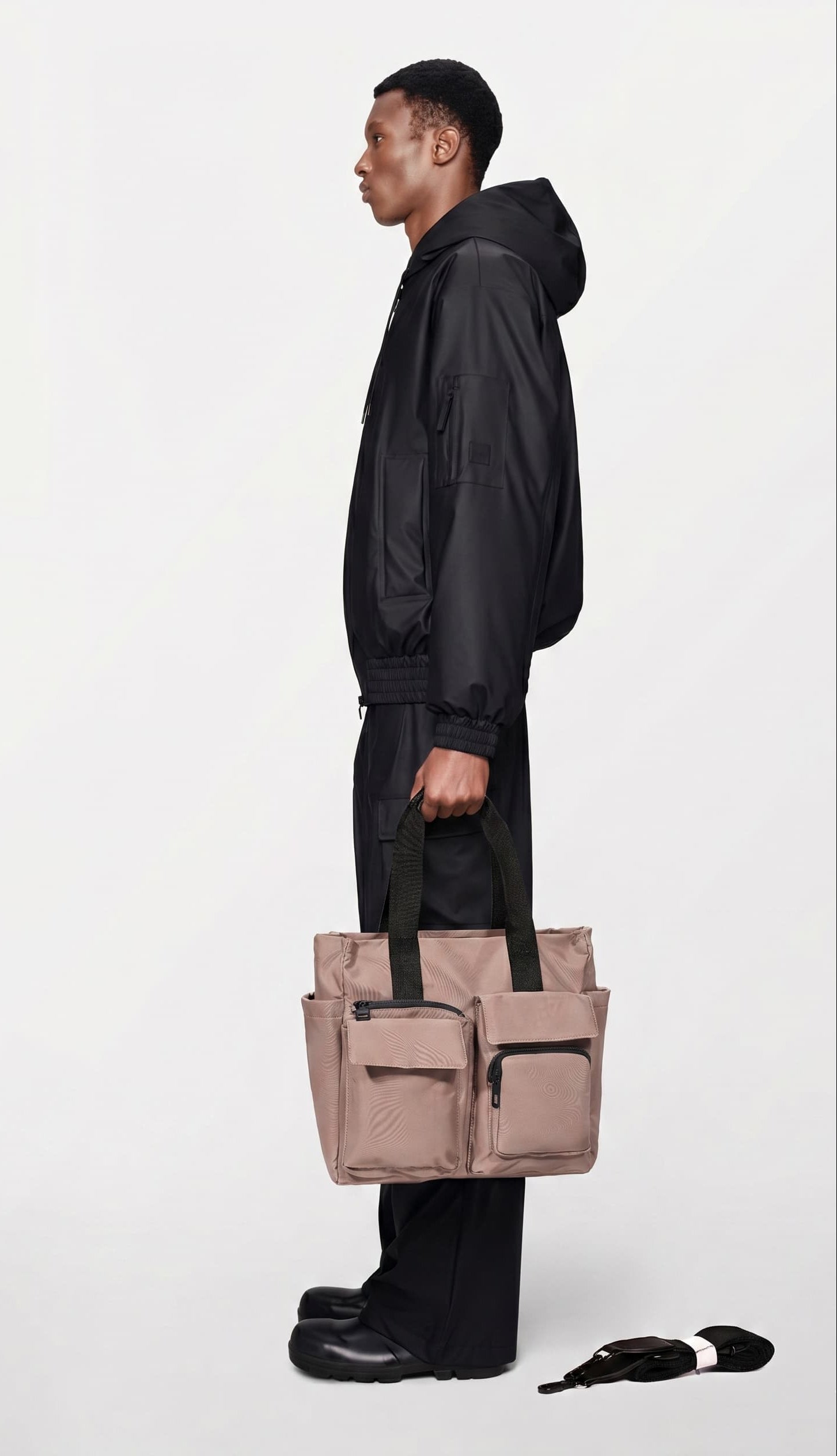 Person holding a beige tote bag against a white background
