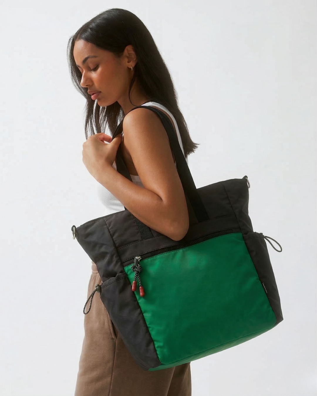 Woman carrying a black and green tote bag on a white background