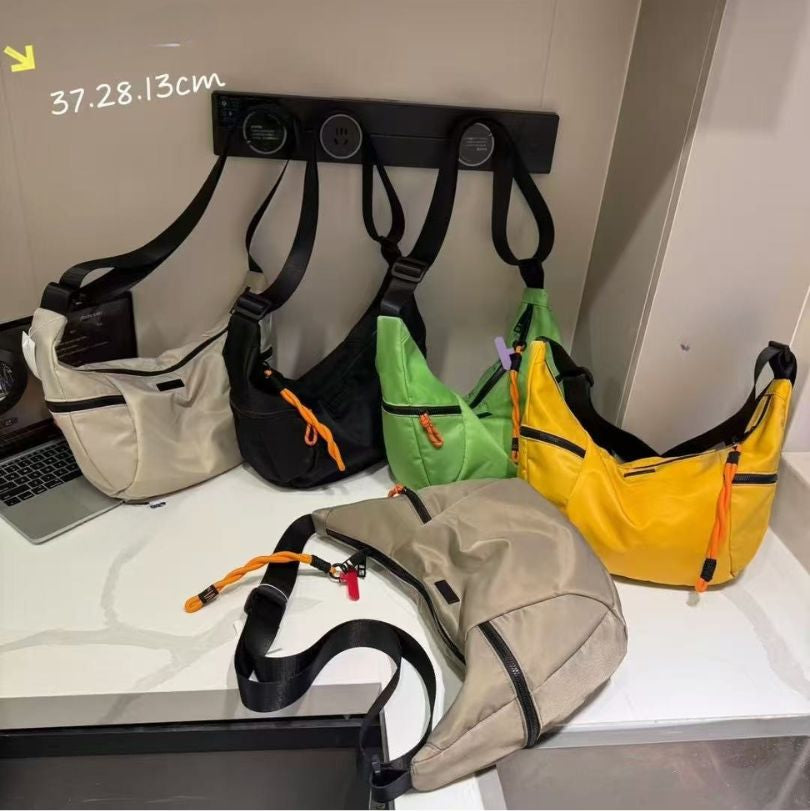 Five colorful bags on a white surface with a measuring label.Black bag with orange interior on a light gray background.Waterproof tote bag with a durable exterior and a bright orange interior. Features an adjustable strap and multiple pockets for organization. Ideal for travel, gym, or daily use in India.