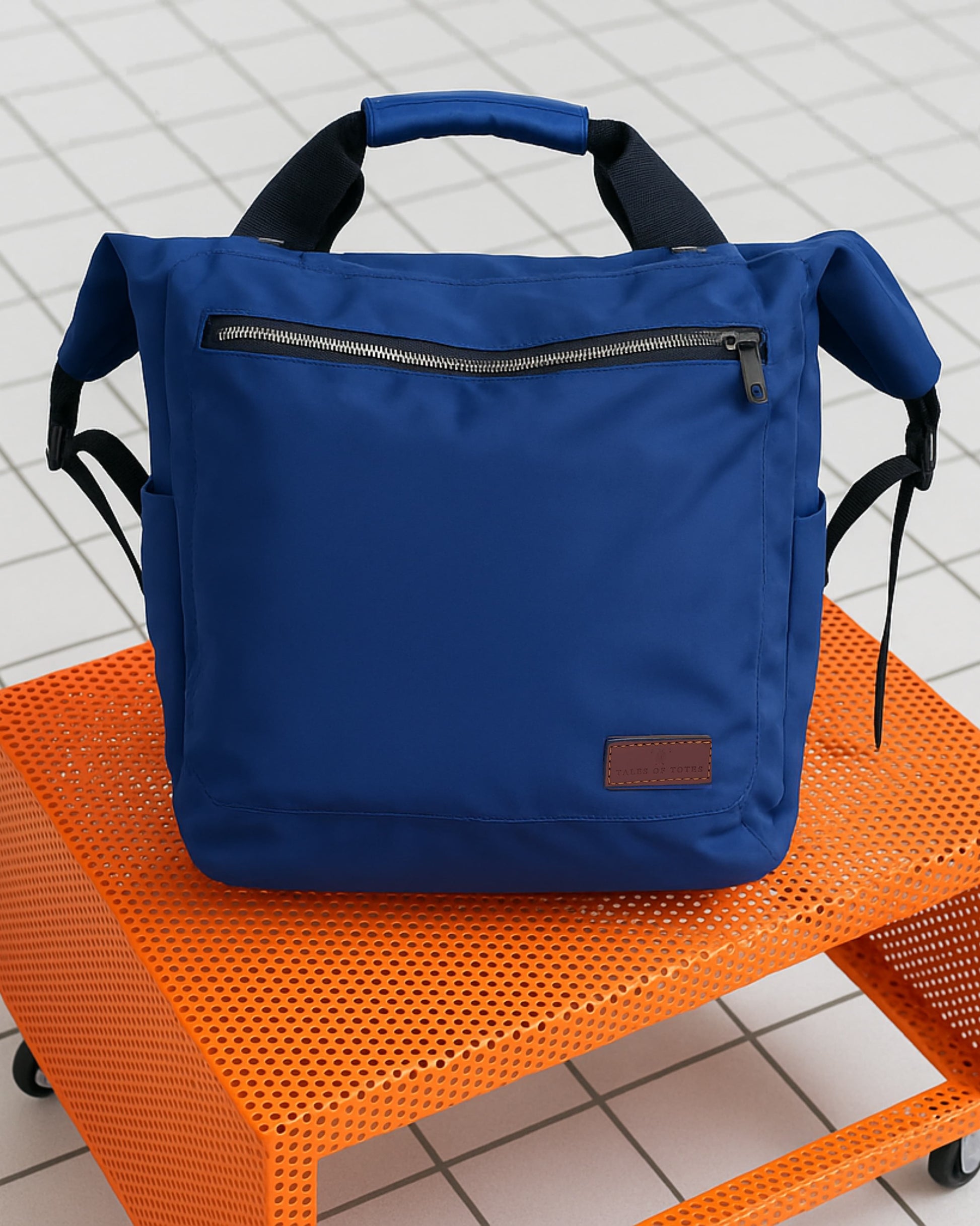 "Modern utility backpack with a structured silhouette, front zip pocket, padded handle, and side compartments – designed for daily commuting, travel, or college use. Features durable water-resistant material, sleek zipper details, and adjustable shoulder straps. A functional and fashion-forward choice from Tales of Totes for urban Indian lifestyles."

