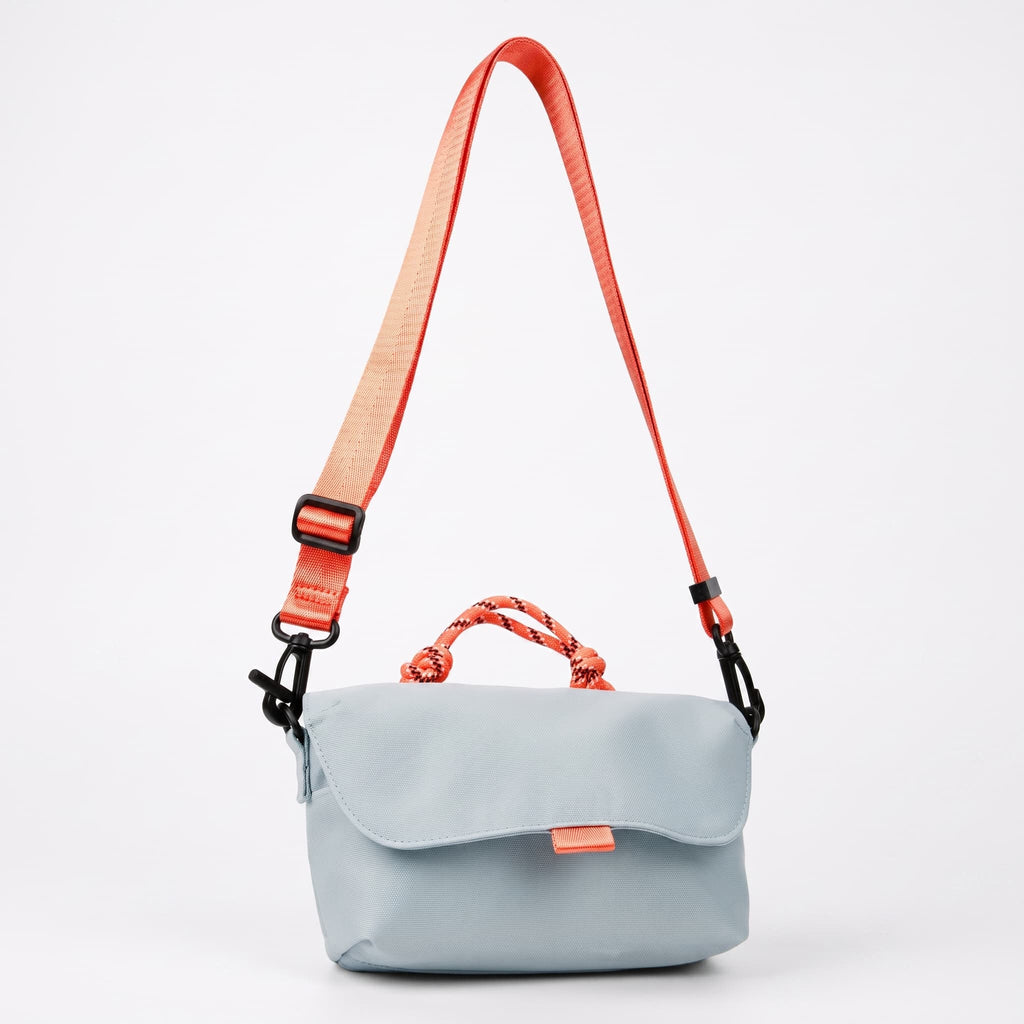 Compact, functional and made to stand out.

Designed for everyday movement, this crossbody bag pairs a clean, softly structured body with contrast utility details. The curved front flap keeps the silhouette minimal, while the bold webbing strap and knotted rope handle give it a sporty, technical edge.

Wear it crossbody for everyday errands, over the shoulder, or carry it by the rope handle when you want to switch things up. Lightweight and easy to style, it’s sized for your daily essentials without feeling