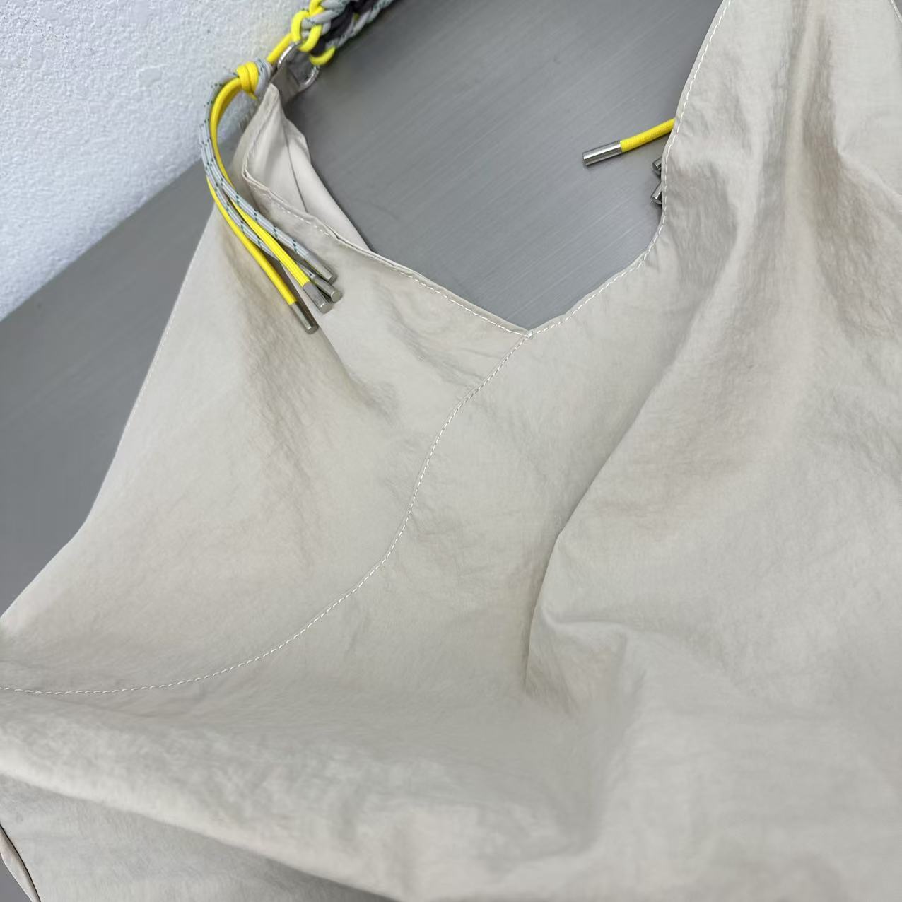 Light gray tank top with yellow straps on a gray background Person holding a gray tote bag in an indoor setting,“Trendy tote bag for women in India with spacious design, inner pocket, and rope handle strap – perfect everyday alternative to Zara tote bags, H&M shopper bags, Mango handbags, Charles & Keith totes, Lifestyle handbags, Myntra handbags, and Fabindia casual totes.”