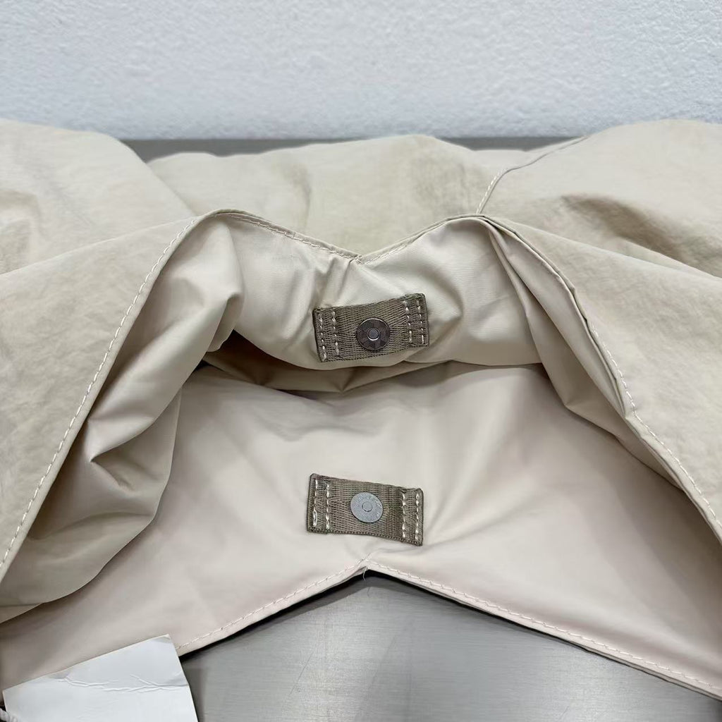 Close-up of a beige fabric with a button and label on a light gray background,Person holding a gray tote bag in an indoor setting,“Trendy tote bag for women in India with spacious design, inner pocket, and rope handle strap – perfect everyday alternative to Zara tote bags, H&M shopper bags, Mango handbags, Charles & Keith totes, Lifestyle handbags, Myntra handbags, and Fabindia casual totes.”