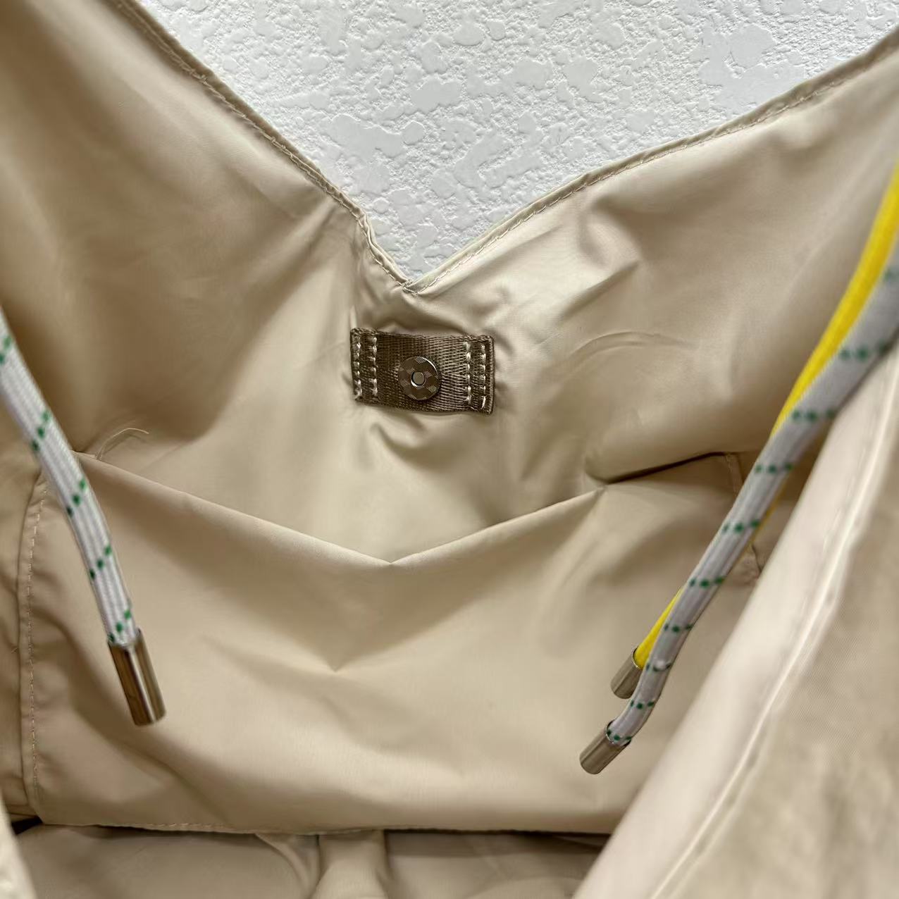 Close-up of a beige jacket with a brand logo on a textured white background,Person holding a gray tote bag in an indoor setting,“Trendy tote bag for women in India with spacious design, inner pocket, and rope handle strap – perfect everyday alternative to Zara tote bags, H&M shopper bags, Mango handbags, Charles & Keith totes, Lifestyle handbags, Myntra handbags, and Fabindia casual totes.”