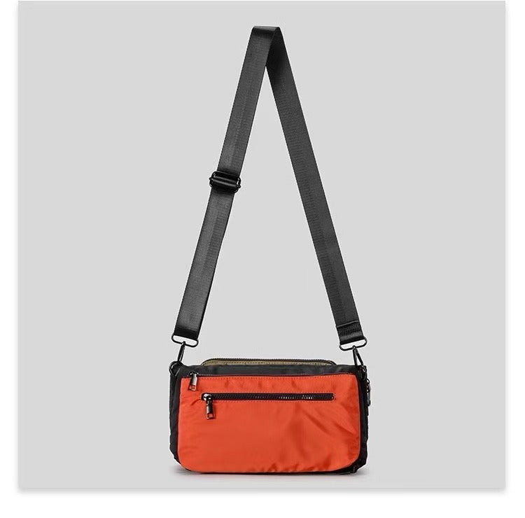 Orange crossbody bag with a black strap on a light gray background