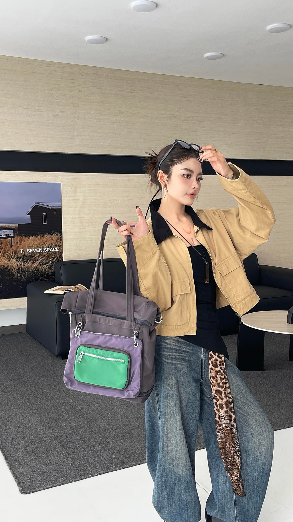 Woman holding a gray tote bag with a green pocket in a modern interior setting