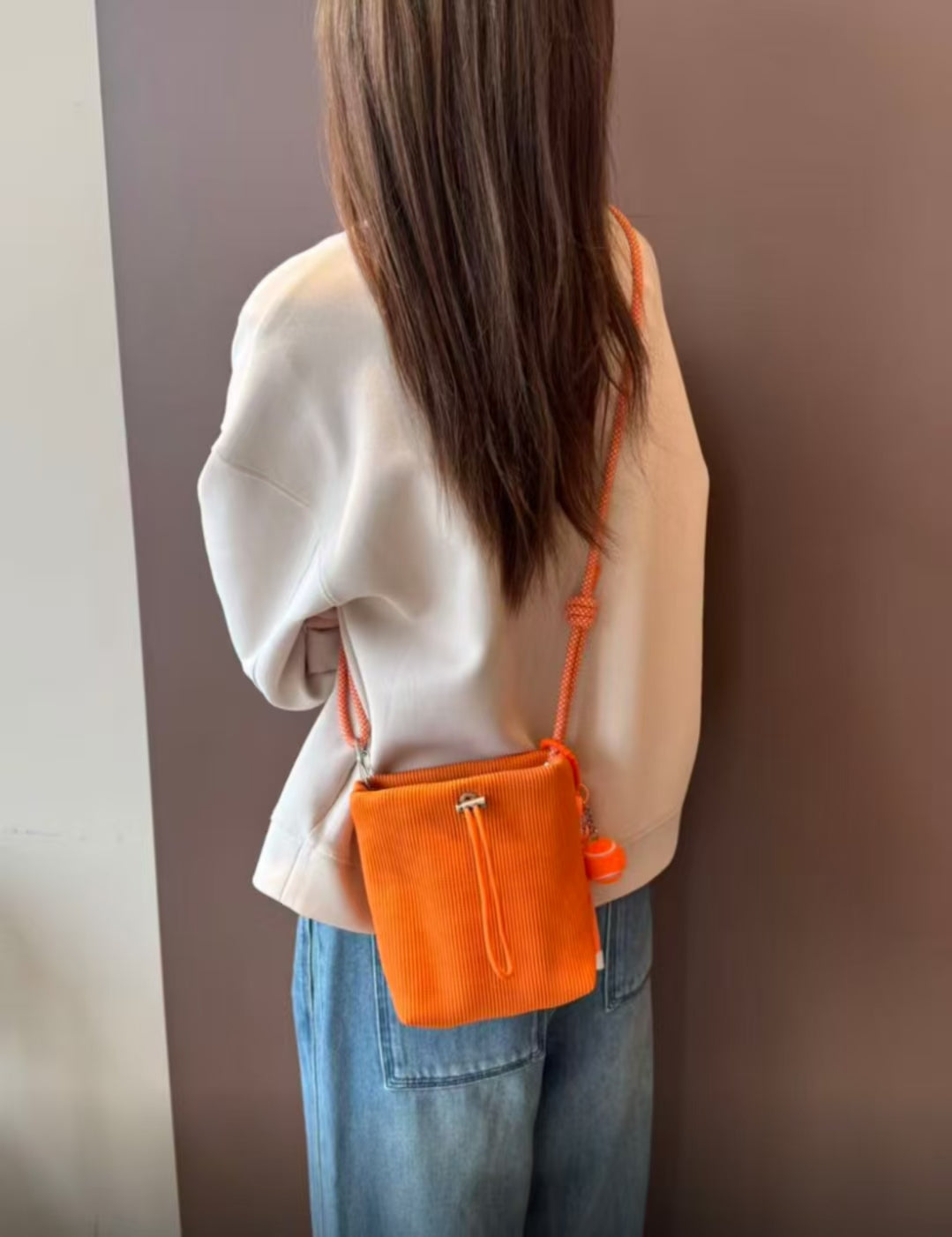 Small in size, strong in character.

This compact sling bag is built around a tall, bucket-style silhouette with a tactile textured outer body and a soft drawstring inner pouch. The long rope strap keeps the look relaxed and functional, while knotted details and utility hardware give it a more experimental feel than a conventional mini bag.

Designed for days when you only want to carry the essentials, it sits comfortably against the body without feeling bulky. The narrow shape keeps it easy to move around 