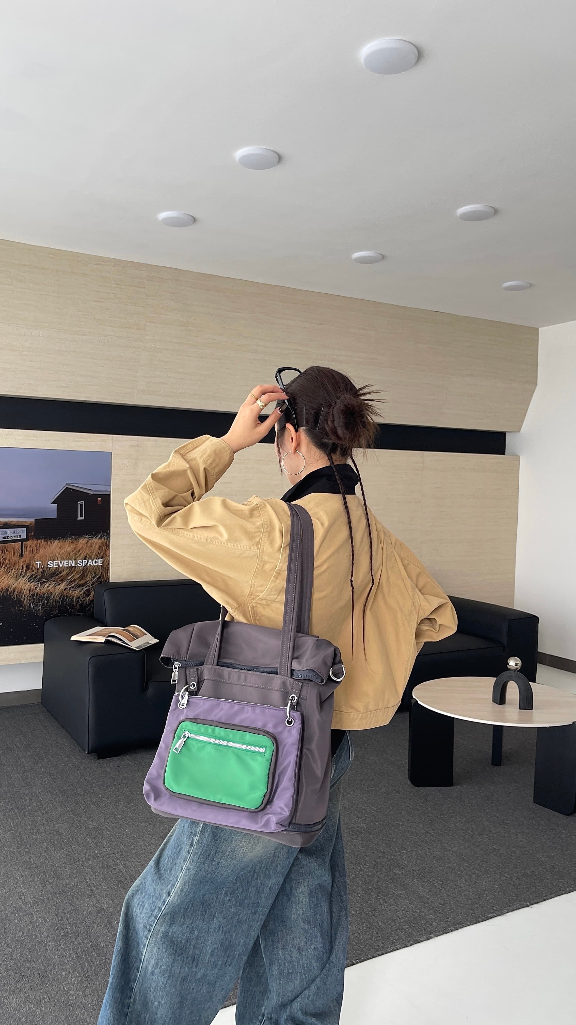 Person holding a purple bag with a green pocket in an indoor setting