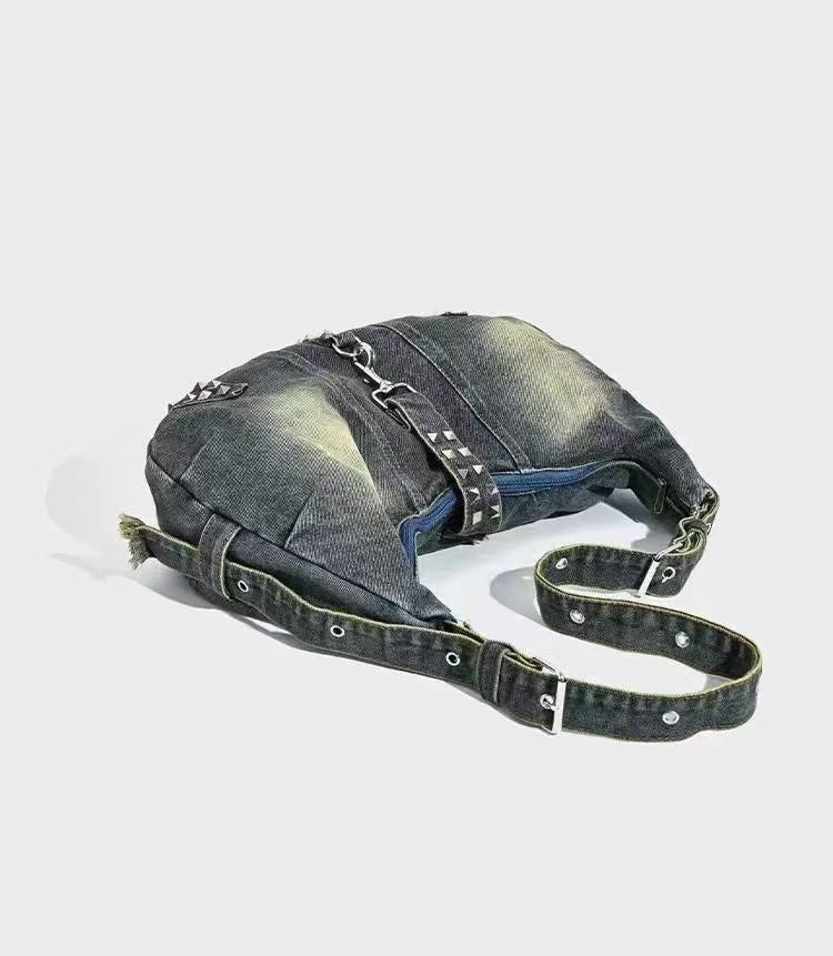Denim bag with metal chain and studs on a white background