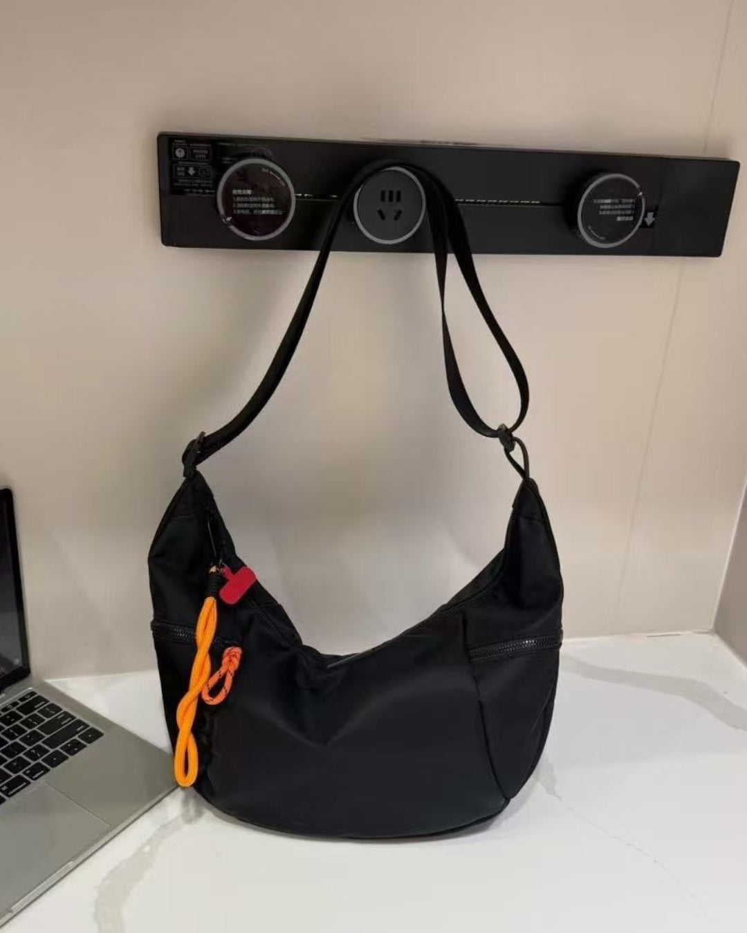 Black bag with orange interior on a light gray background.Waterproof tote bag with a durable exterior and a bright orange interior. Features an adjustable strap and multiple pockets for organization. Ideal for travel, gym, or daily use in India.