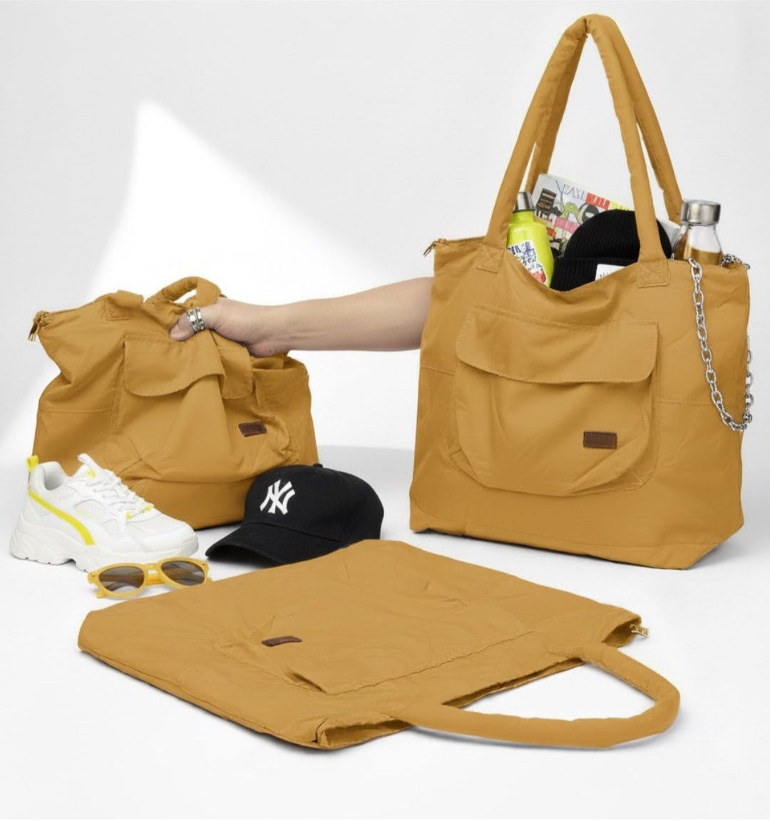 Three mustard yellow handbags with a hand reaching for one of them on a white background.