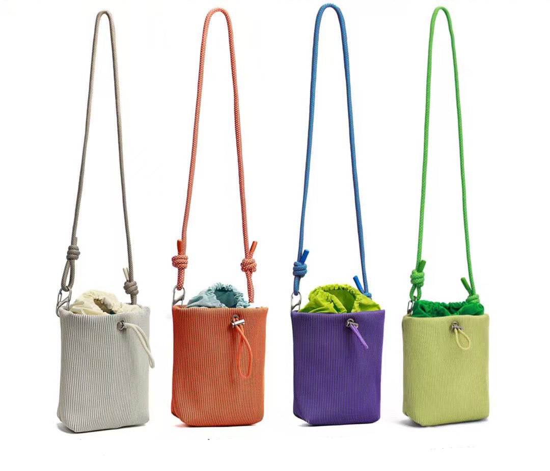 Small in size, strong in character.

This compact sling bag is built around a tall, bucket-style silhouette with a tactile textured outer body and a soft drawstring inner pouch. The long rope strap keeps the look relaxed and functional, while knotted details and utility hardware give it a more experimental feel than a conventional mini bag.

Designed for days when you only want to carry the essentials, it sits comfortably against the body without feeling bulky. The narrow shape keeps it easy to move around 