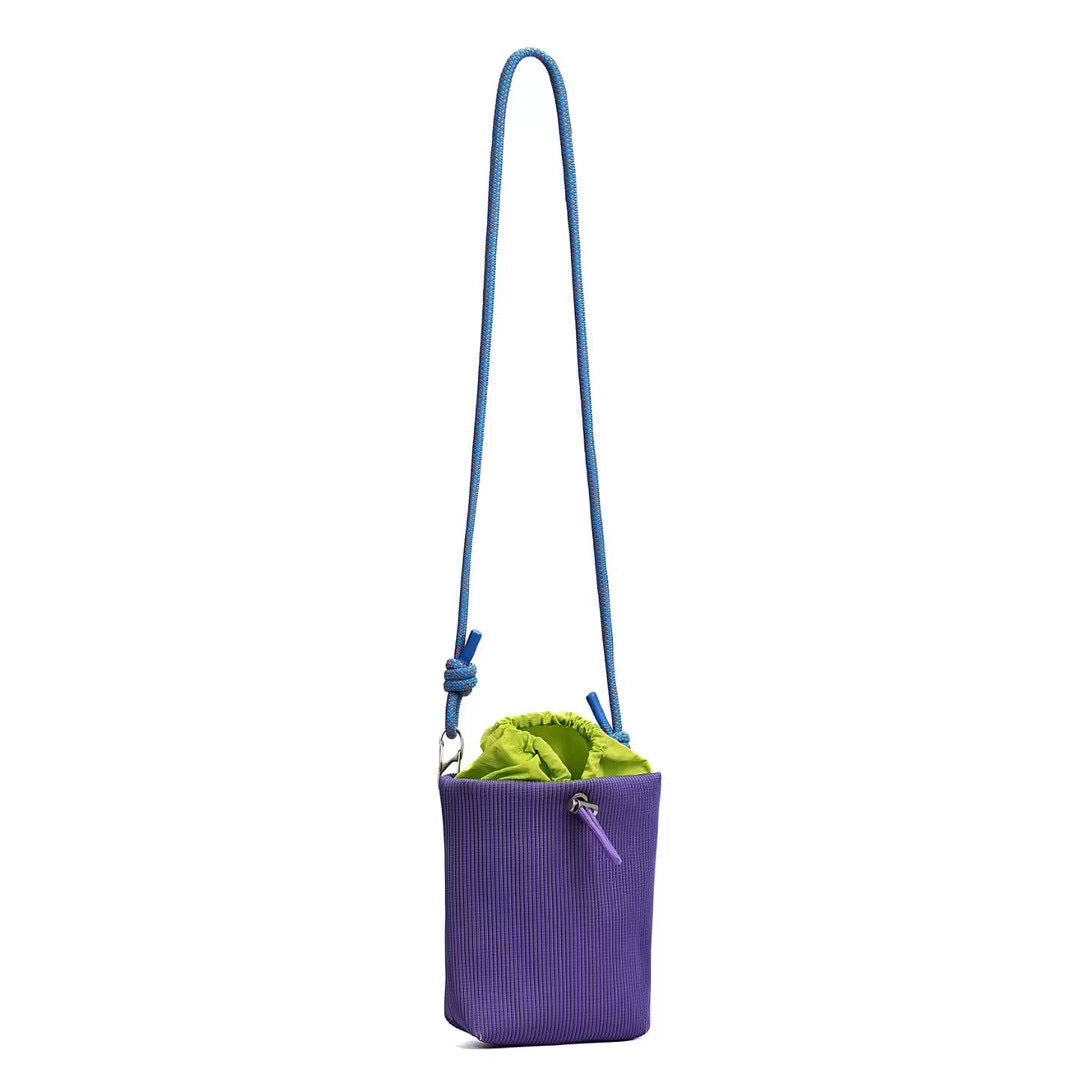 Small in size, strong in character.

This compact sling bag is built around a tall, bucket-style silhouette with a tactile textured outer body and a soft drawstring inner pouch. The long rope strap keeps the look relaxed and functional, while knotted details and utility hardware give it a more experimental feel than a conventional mini bag.

Designed for days when you only want to carry the essentials, it sits comfortably against the body without feeling bulky. The narrow shape keeps it easy to move around 