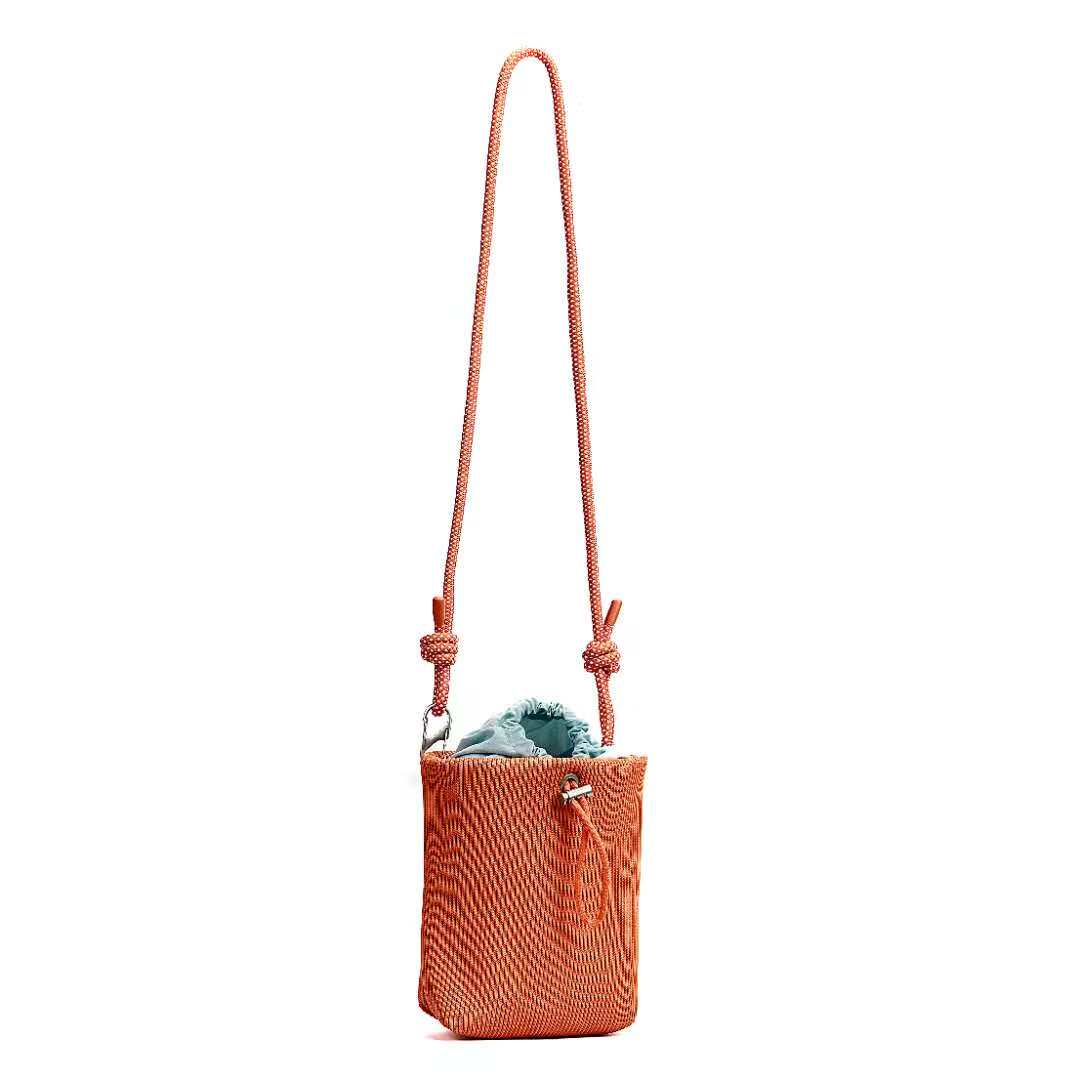 Small in size, strong in character.

This compact sling bag is built around a tall, bucket-style silhouette with a tactile textured outer body and a soft drawstring inner pouch. The long rope strap keeps the look relaxed and functional, while knotted details and utility hardware give it a more experimental feel than a conventional mini bag.

Designed for days when you only want to carry the essentials, it sits comfortably against the body without feeling bulky. The narrow shape keeps it easy to move around 