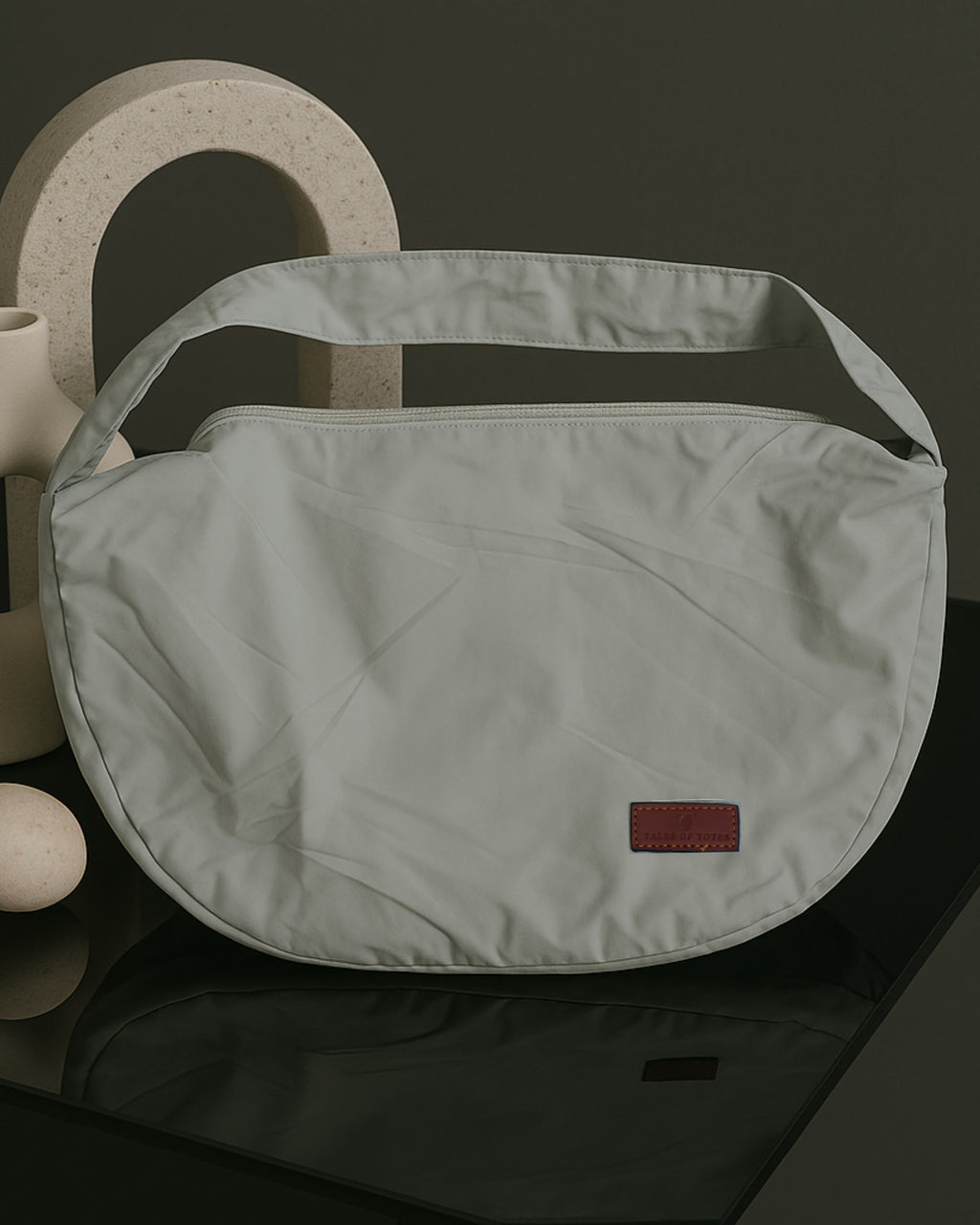 Half-moon shaped crossbody tote bag made from lightweight, water-resistant fabric – features a wide adjustable strap and secure top zipper closure. Minimalist design ideal for everyday carry, travel, or streetwear looks. A functional and fashion-forward piece from Tales of Totes, offering elevated casual utility for modern Indian shoppers."